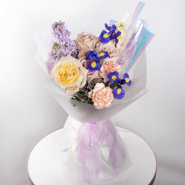 Irises - 3, Matthiola Lilac - 3, Rose Yellow 50 cm Ecuador (Mohana, Latina, Brighton) - 1, Cream Rose 50 cm Ecuador (Creme Caramel) - 3, Carnation white, cream - 8, White Matthiola - 2, Limonium (1 pc.), Pistachio, Wrapping Paper