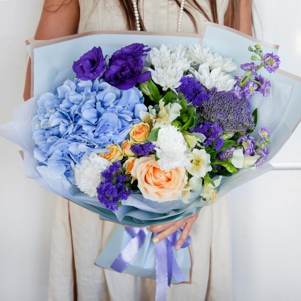 Matthiola Lilac - 2, Rose Cream 50 cm - 1, Carnation white, cream - 2, Spray rose: white, cream, light pink 50 cm - 1, Blue/purple hydrangea - 1, Alstromeria white, soft pink - 2, Baltica White Spray Chrysanthemum - 1, Purple Lisianthus (Eustoma) - 1, Trachelium, Blue Statice, Wrapping Paper
